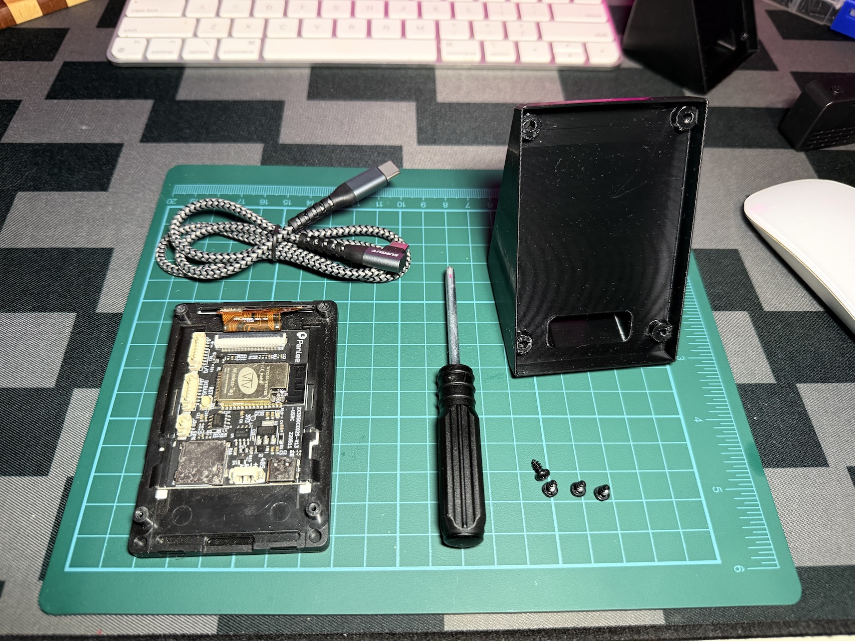 The board with its back cover off, a right-angle USB-C cable, a screwdriver, the printed stand and four screws