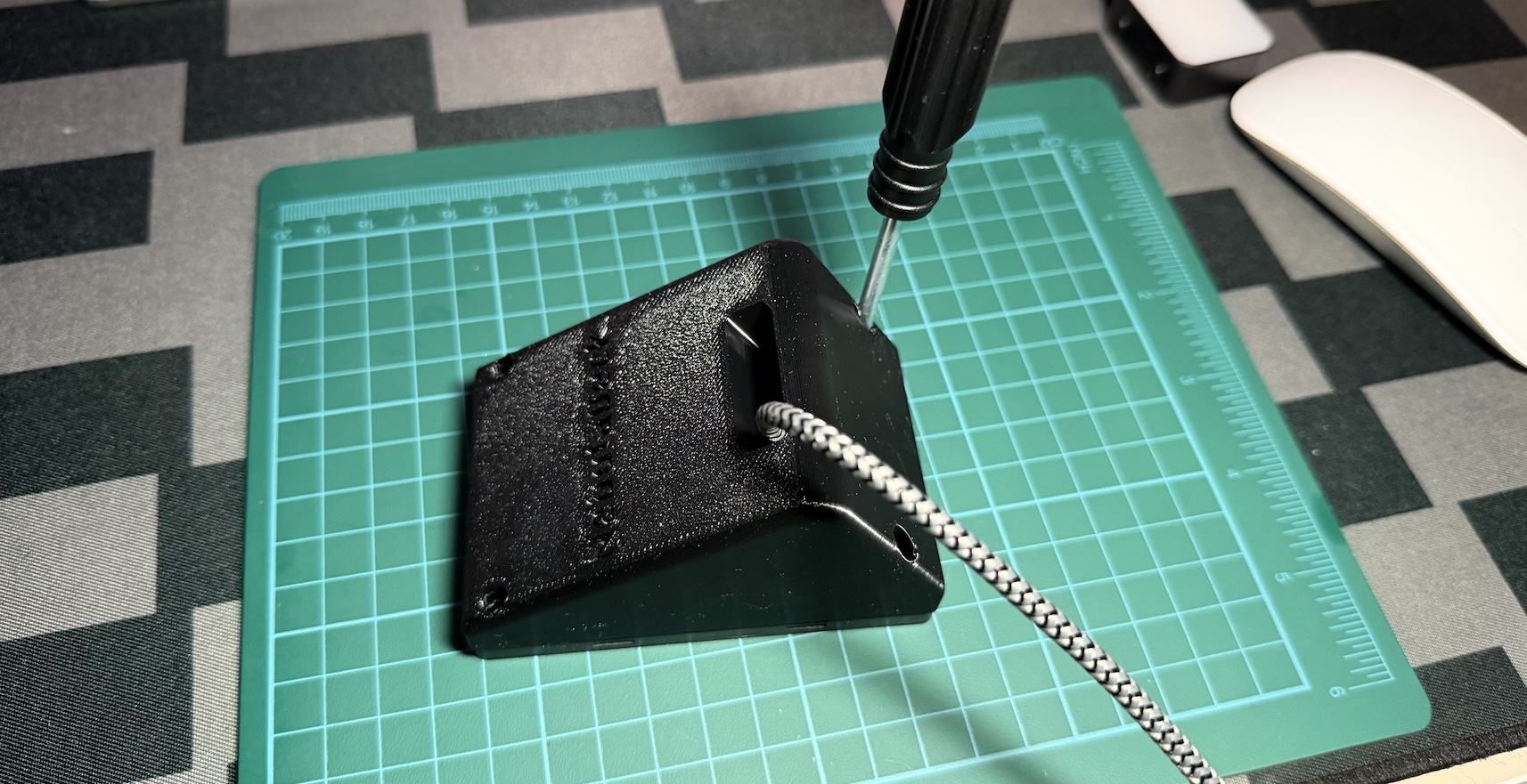 The stand sitting on the board, a screwdriver driving a screw into a corner